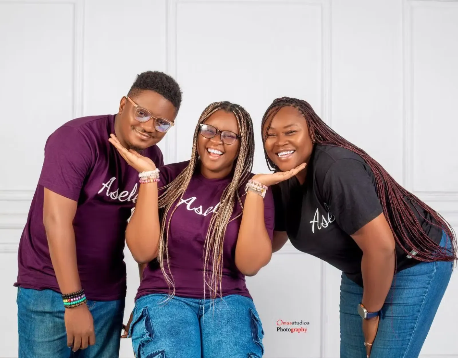 Three Asele team members in branded tees smiling in a studio portrait